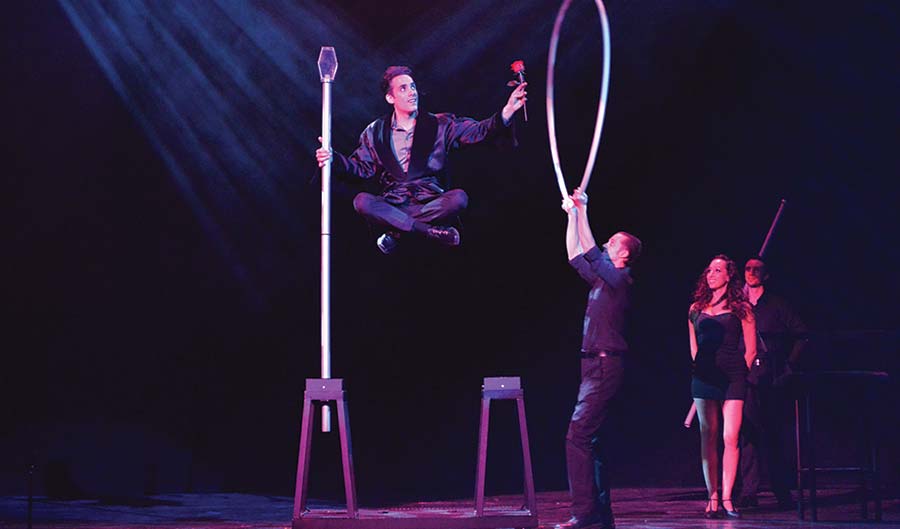 Magician Michael Grandinetti levitating on stage.