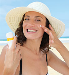 Woman applying sunscreen to her face.