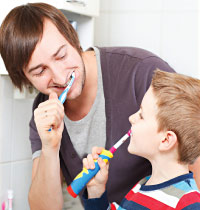 Father brushing teeth with child.