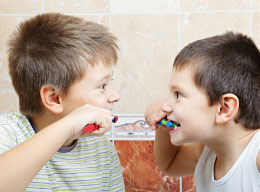 Brothers learning how to brush from eachother.