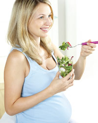 Pregnant woman eating salad.