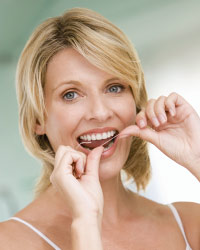 Pregnant woman flossing teeth.