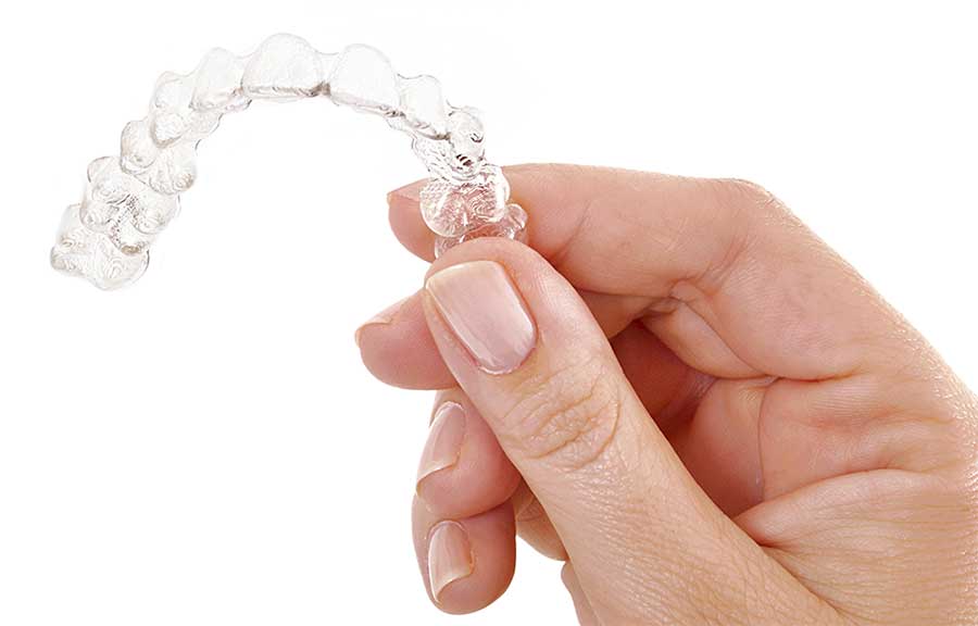 Person holding an Invisalign Aligner.